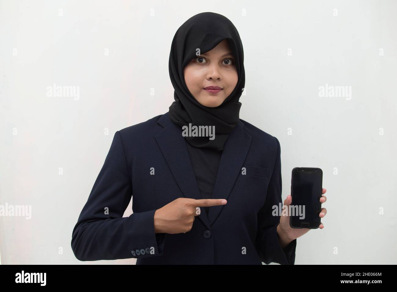 Happy Asian woman in hijab demonstrating mobile cell phone. Portrait of ...