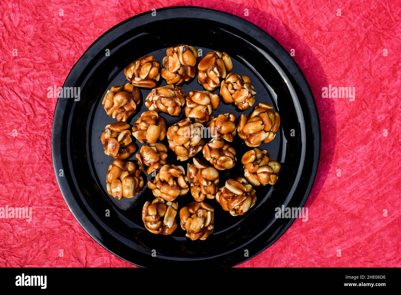 Tasty Peanut ladoo of small size sweet balls. Indian festival makarsankranti special item on red backgroud space to write text fonts. Sweet singhdana Stock Photo