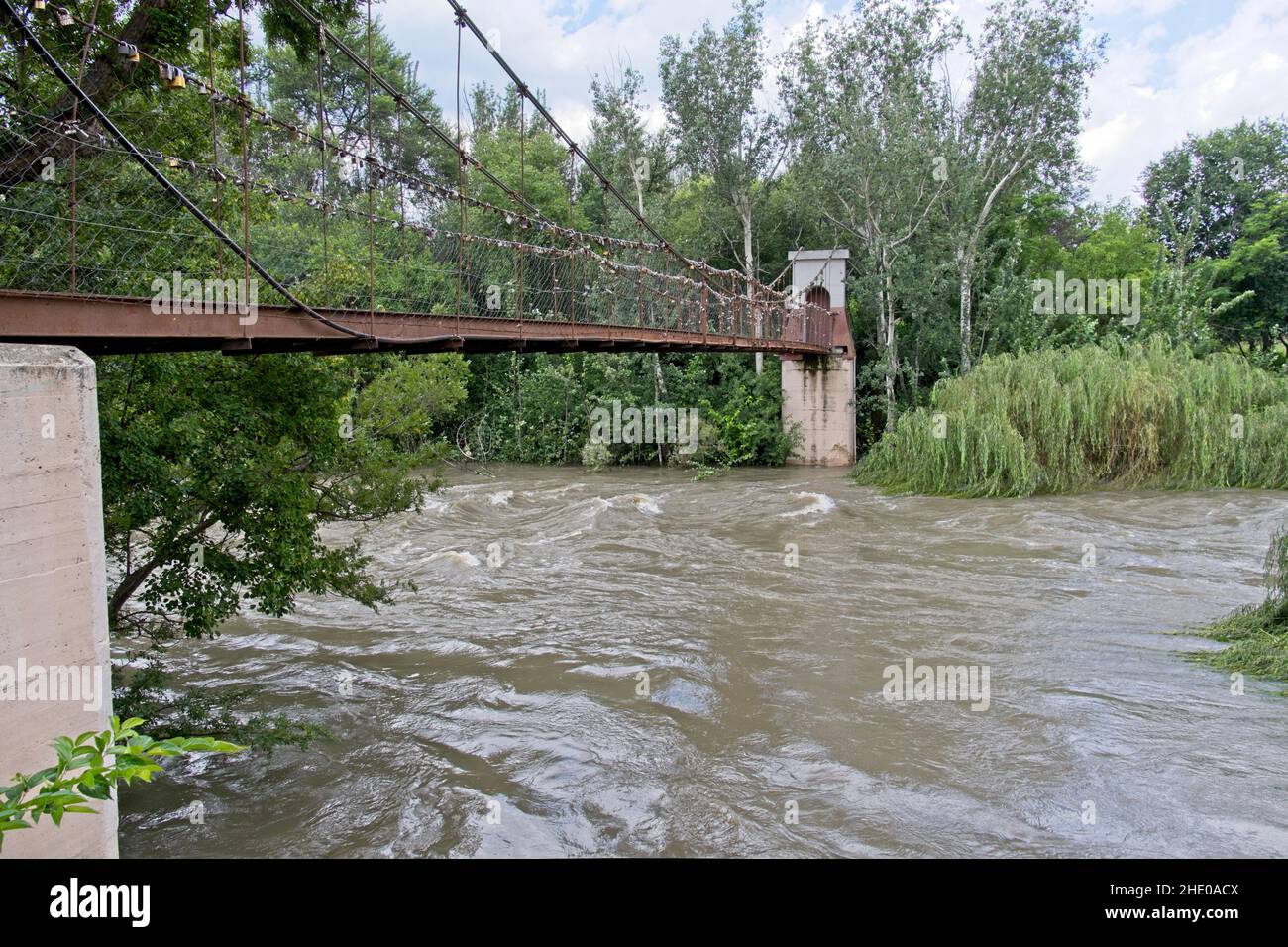Vaal river in flood flowing under historical foot bridge at Parys