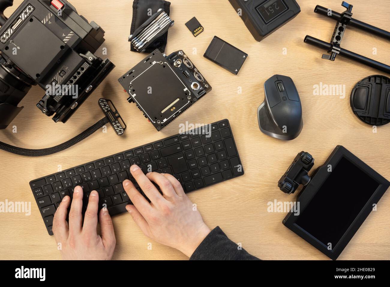 Man typing on computer keyboard by filming equipment at table Stock Photo