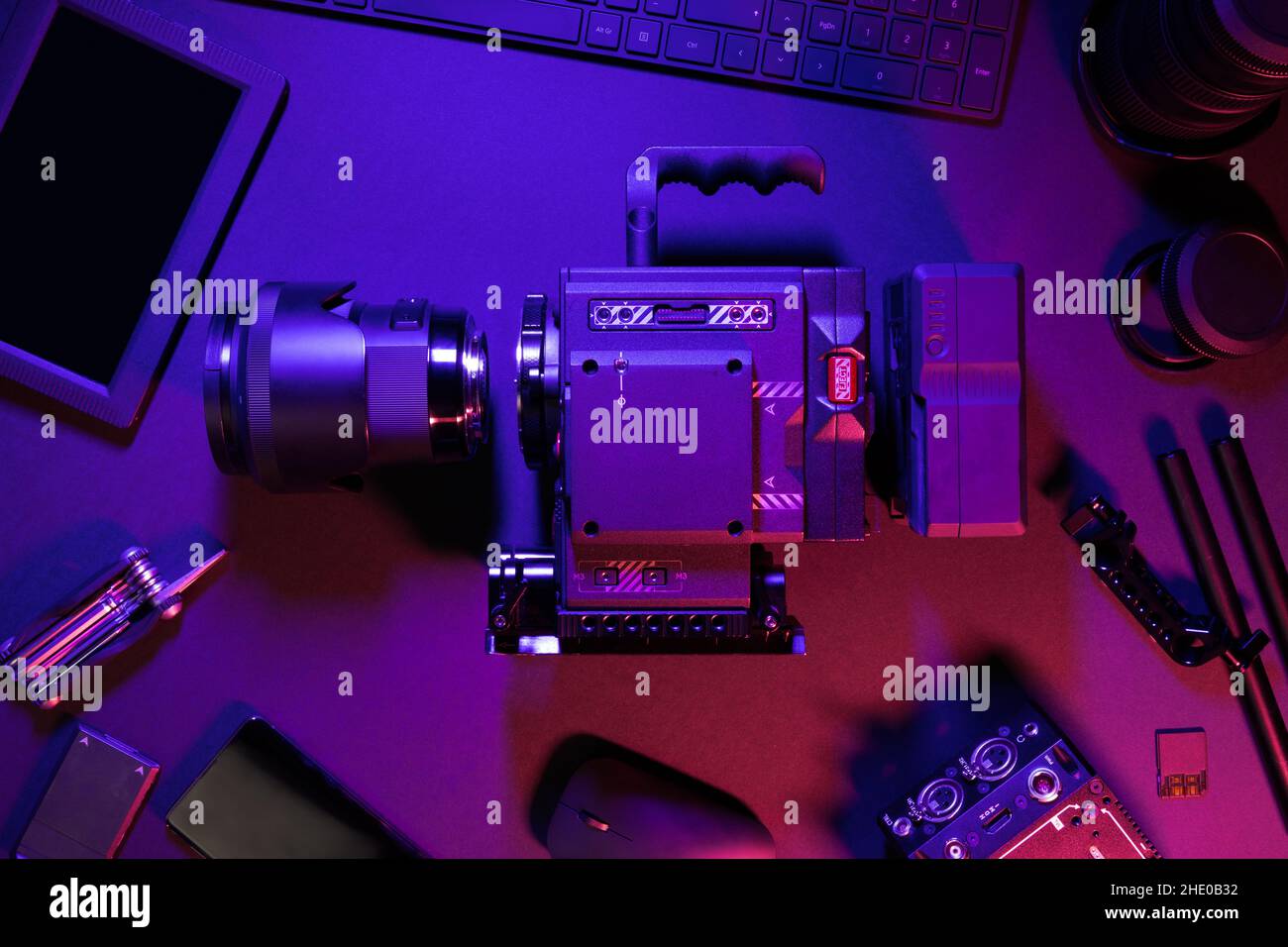 Overhead view of cinema camera and computer parts on colorful illuminated table Stock Photo
