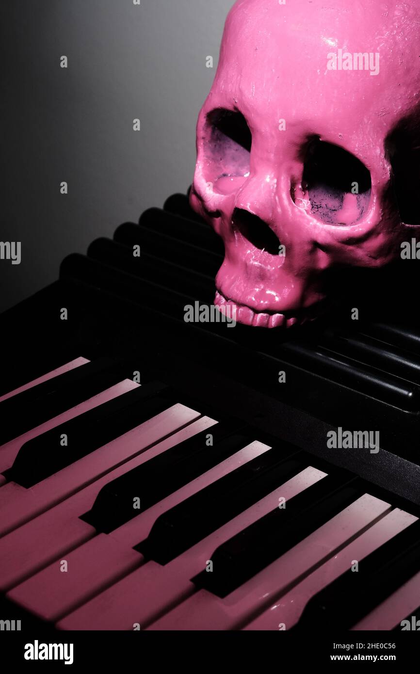 Pink human skull on electric piano keyboard for scary musical performance Stock Photo