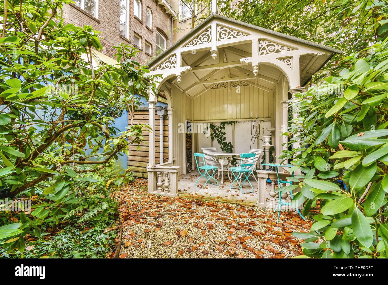Cozy courtyard of the house with green trees and bushes and a white ...