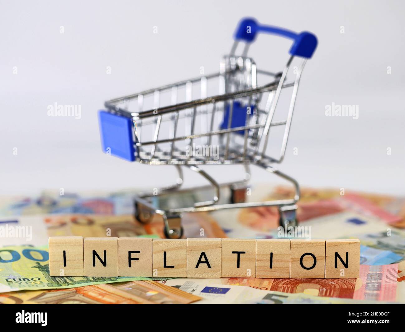 Word INFLATION, written with wooden letter blocks, with shopping cart and euro banknotes on a white background Stock Photo