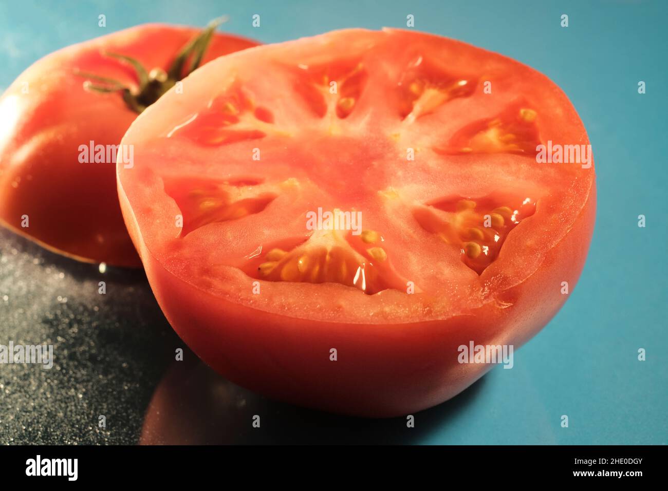 Macro sliced jersey tomato on blue background Stock Photo