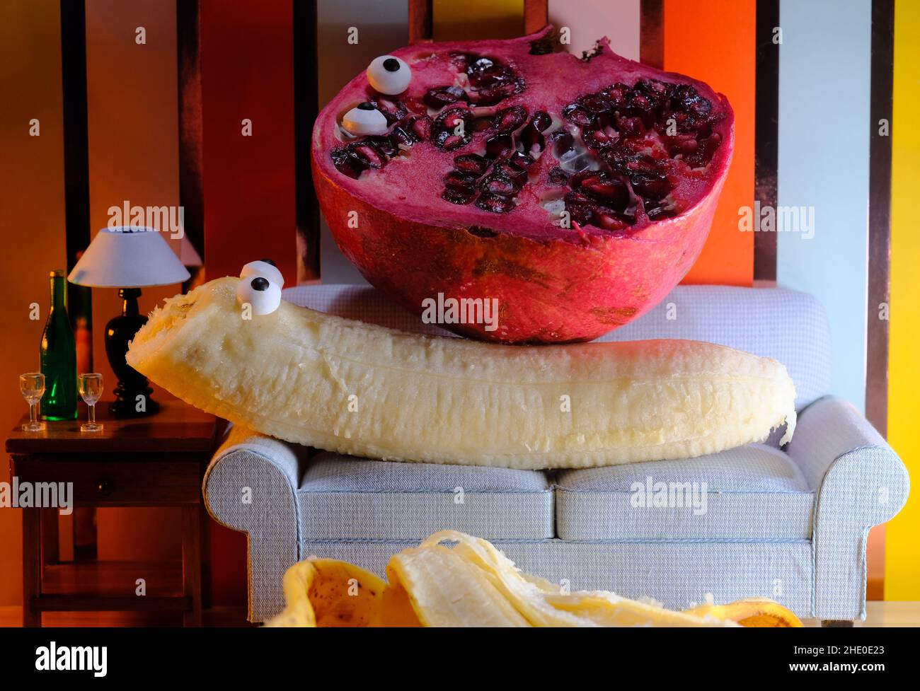 Anthropomorphic pomegranate and banana having an intimate experience on the couch Stock Photo