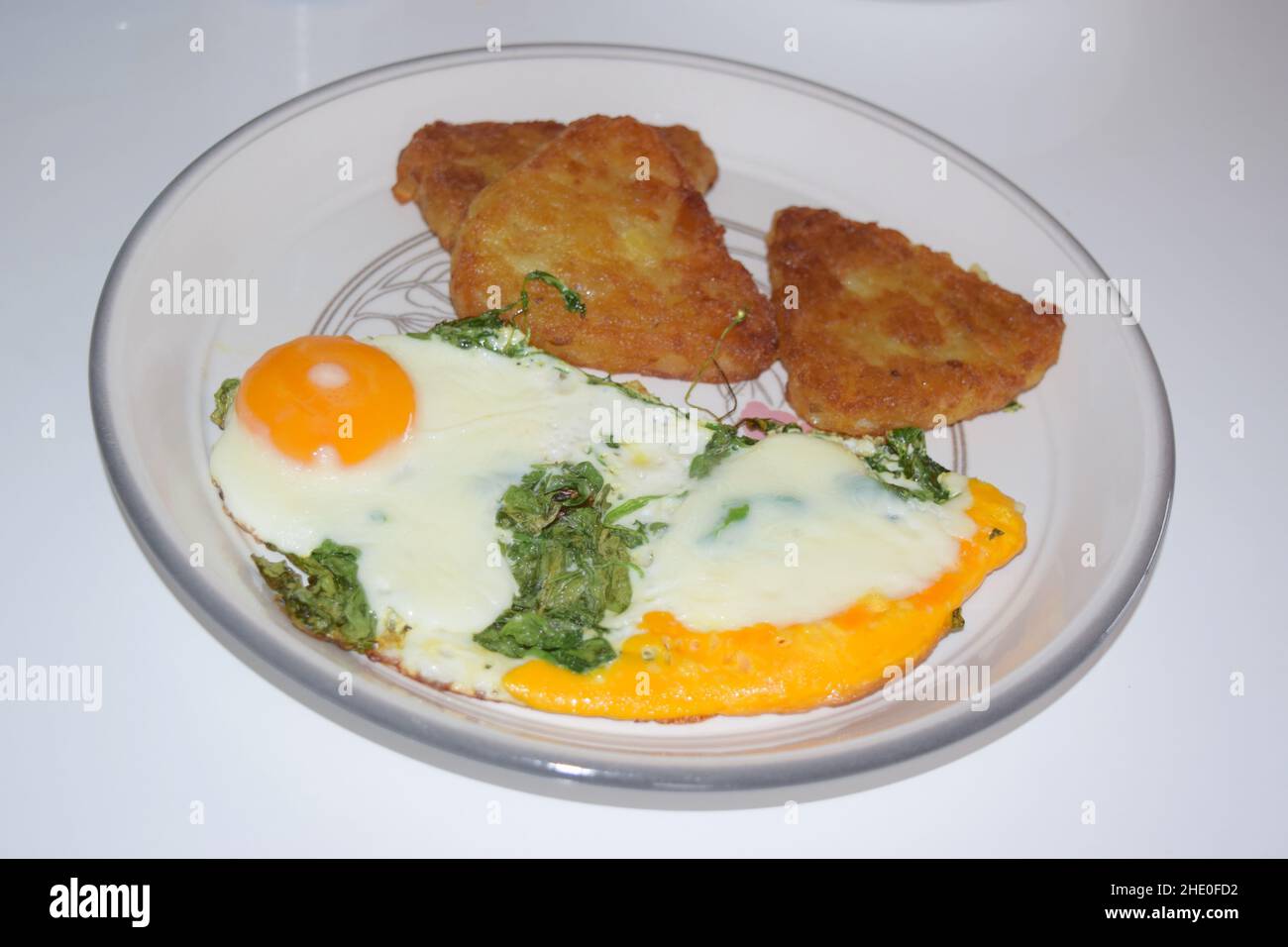 Fried eggs with spinach and hash browns Stock Photo Alamy
