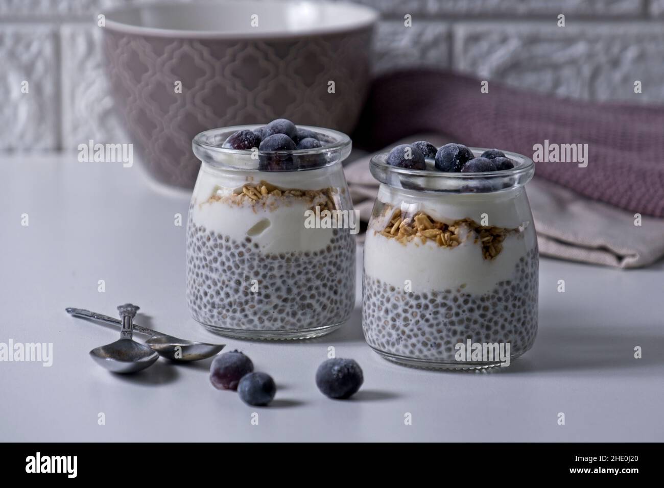 Chia seeds with yoghurt topped with frozen blueberries on white table