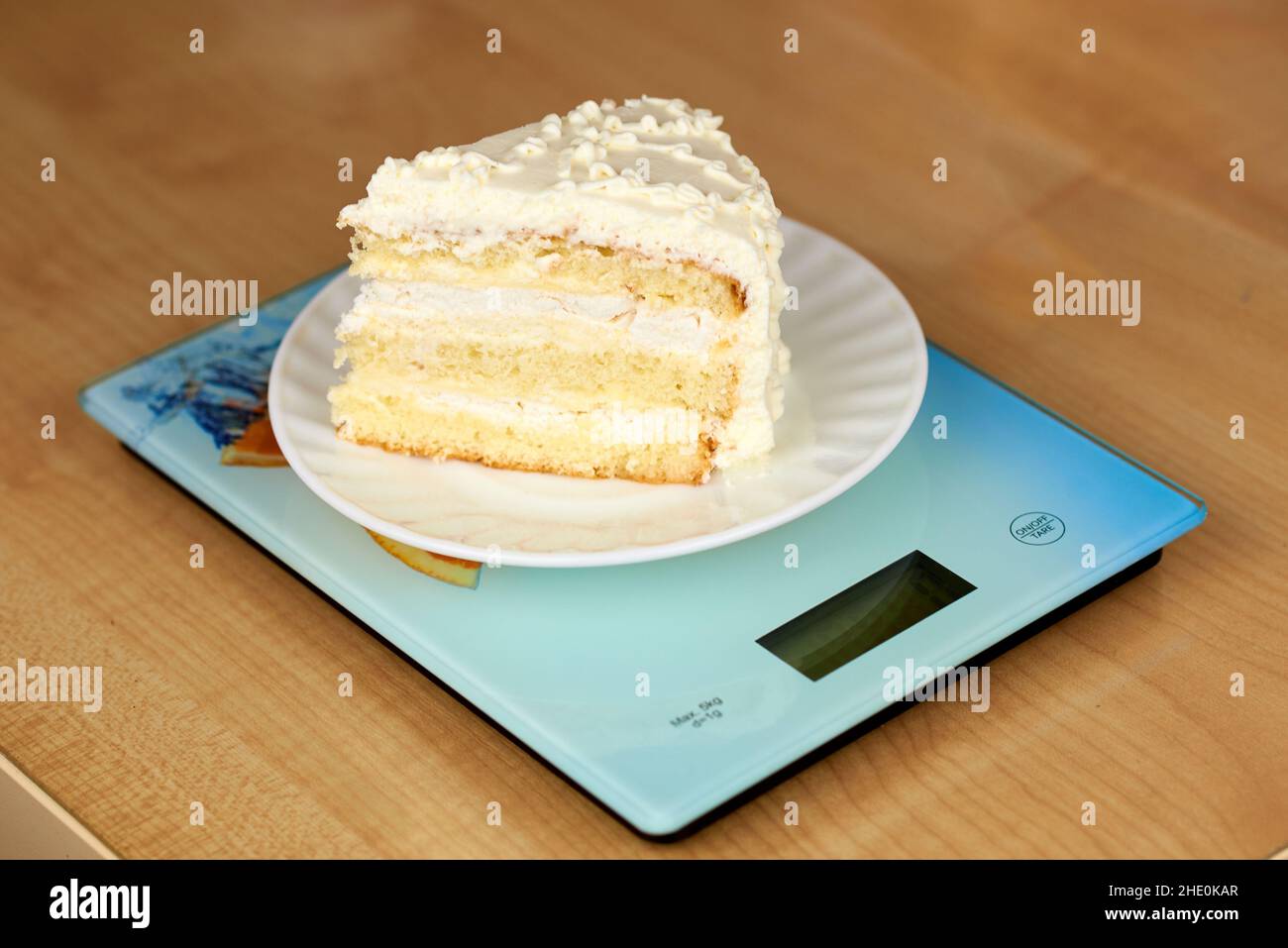 A piece of delicious cake with white butter cream lies on the scales