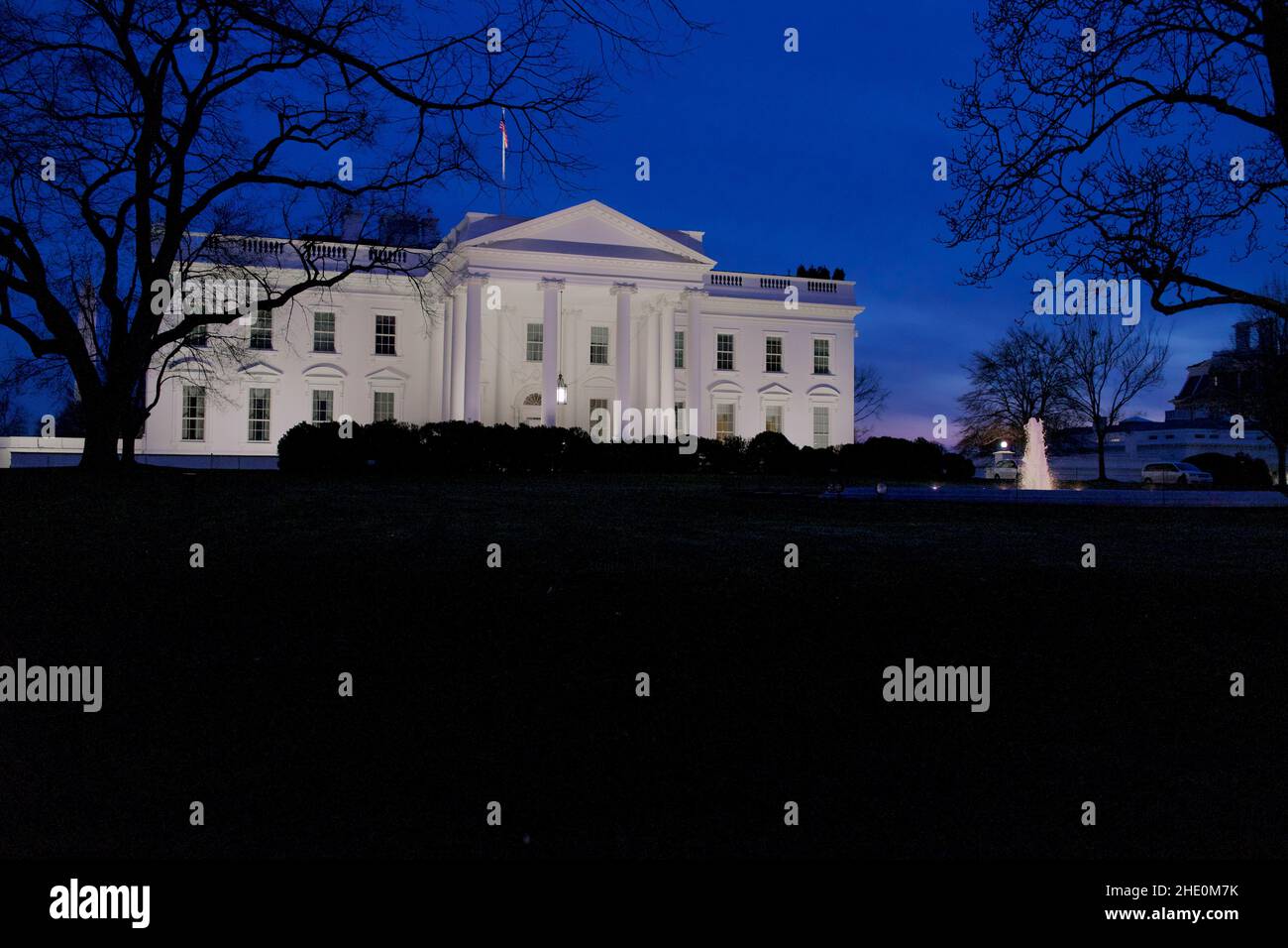White House lit by outside lights at dusk with deep blue sky.  Good copy space at bottom of frame. Stock Photo