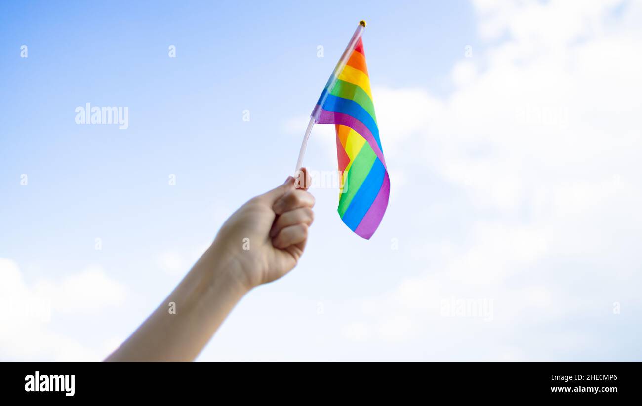 LGBT community. Small lgbt flag in the hand against the blue sky Stock Photo
