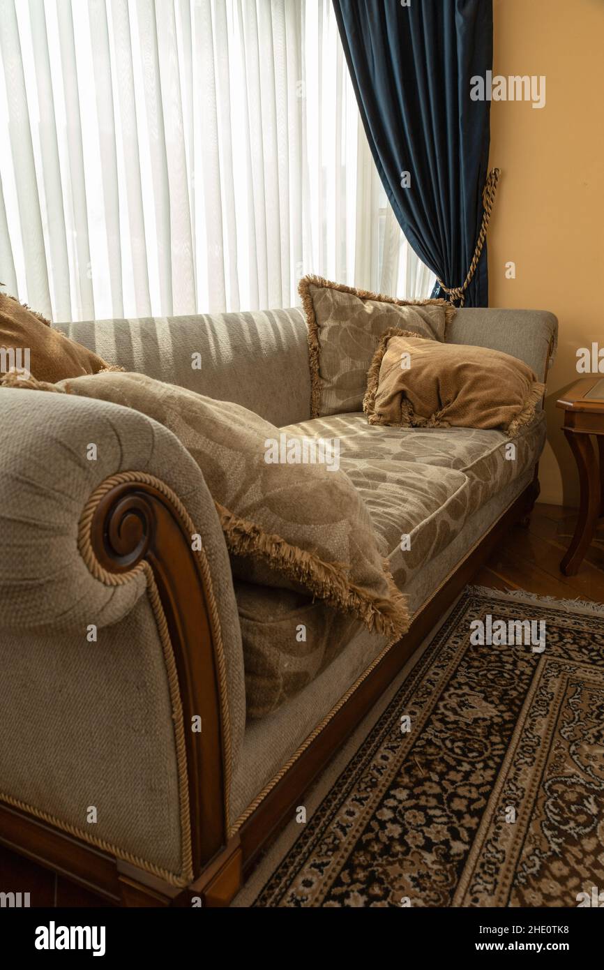 comfortable and elegant sofa decorated with patterned cushions, next to a window with curtains, home interior decoration, fabric and furniture details Stock Photo