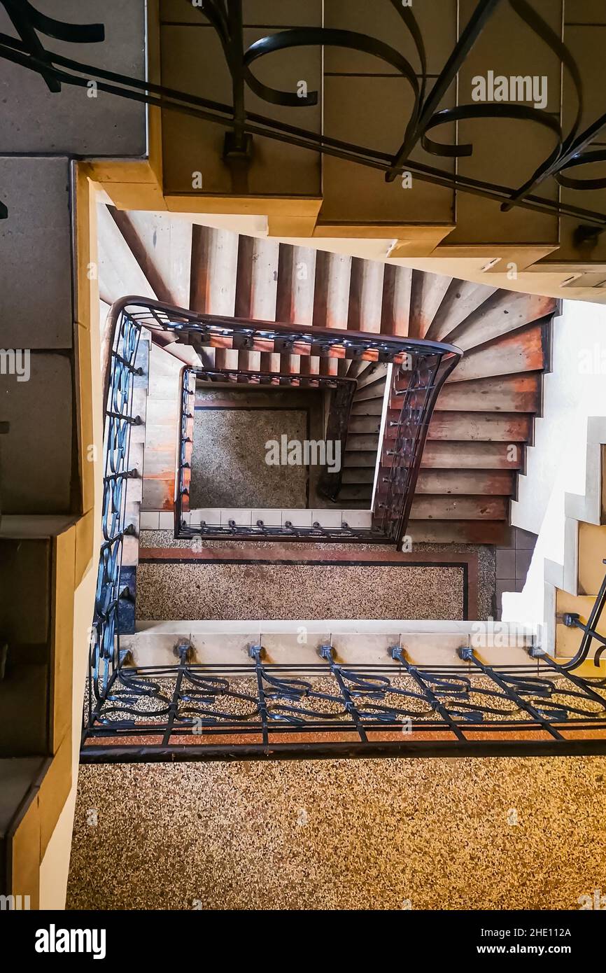 Spiral rectangle staircase with metal railings and covering on the floor of steps Stock Photo