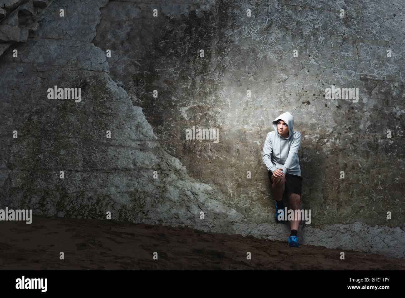 Serious thoughtful hispanic sportsman resting against a natural wall Stock Photo