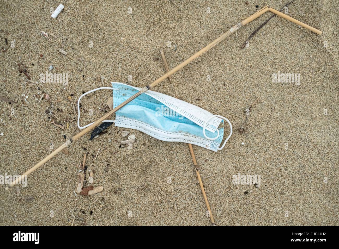 Used surgical face mask discarded on sea coast ecosystem,covid19 pandemic disease pollution waste Stock Photo