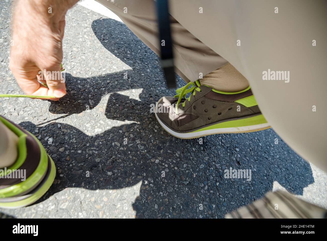 Office worker male shoelace tying on asphalt - low angle POV view Stock Photo