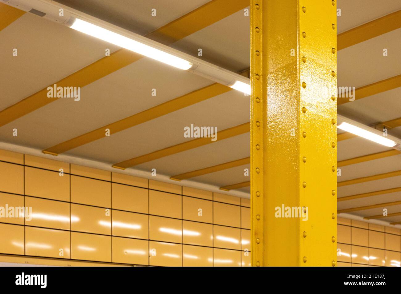 Closeup of a vertical yellow metal pole with a modern white ceiling in U Weberwiese station, Germany Stock Photo