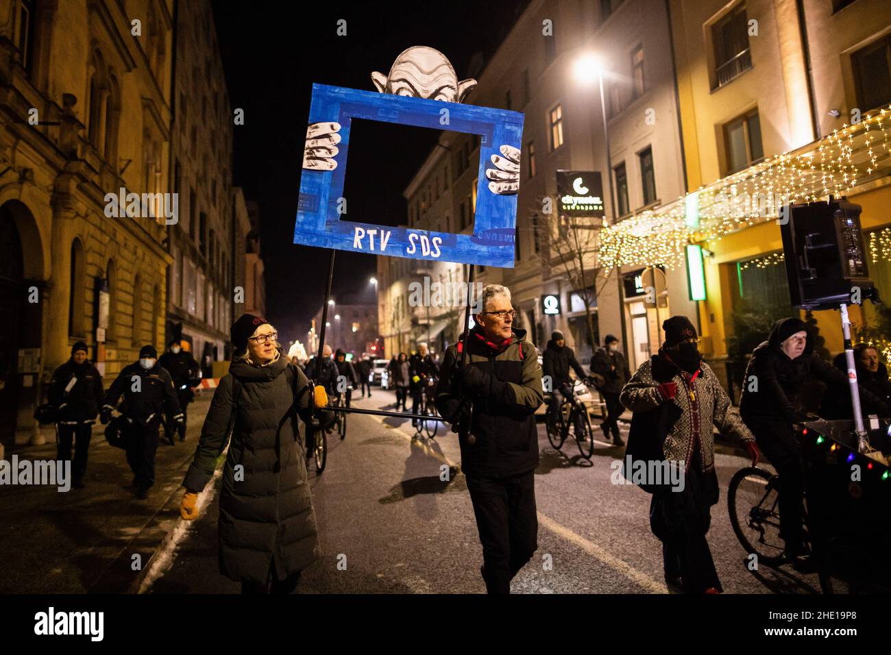 Protesters carry a placard depicting a TV screen with initials of the leading government party Slovenian Democratic Party(SDS), being held by a caricature of the Prime Minister Janez Jansa as they march the streets during an anti-government protest.For the 90th consecutive Friday, people in Ljubljana have protested against the government of Prime Minister Janez Jansa and its alleged dismantling of democracy in the country. The latest protest addressed the national television's management refusing to renew contracts to an entire ensemble of columnists for a critical TV programme Studio City, wh Stock Photo