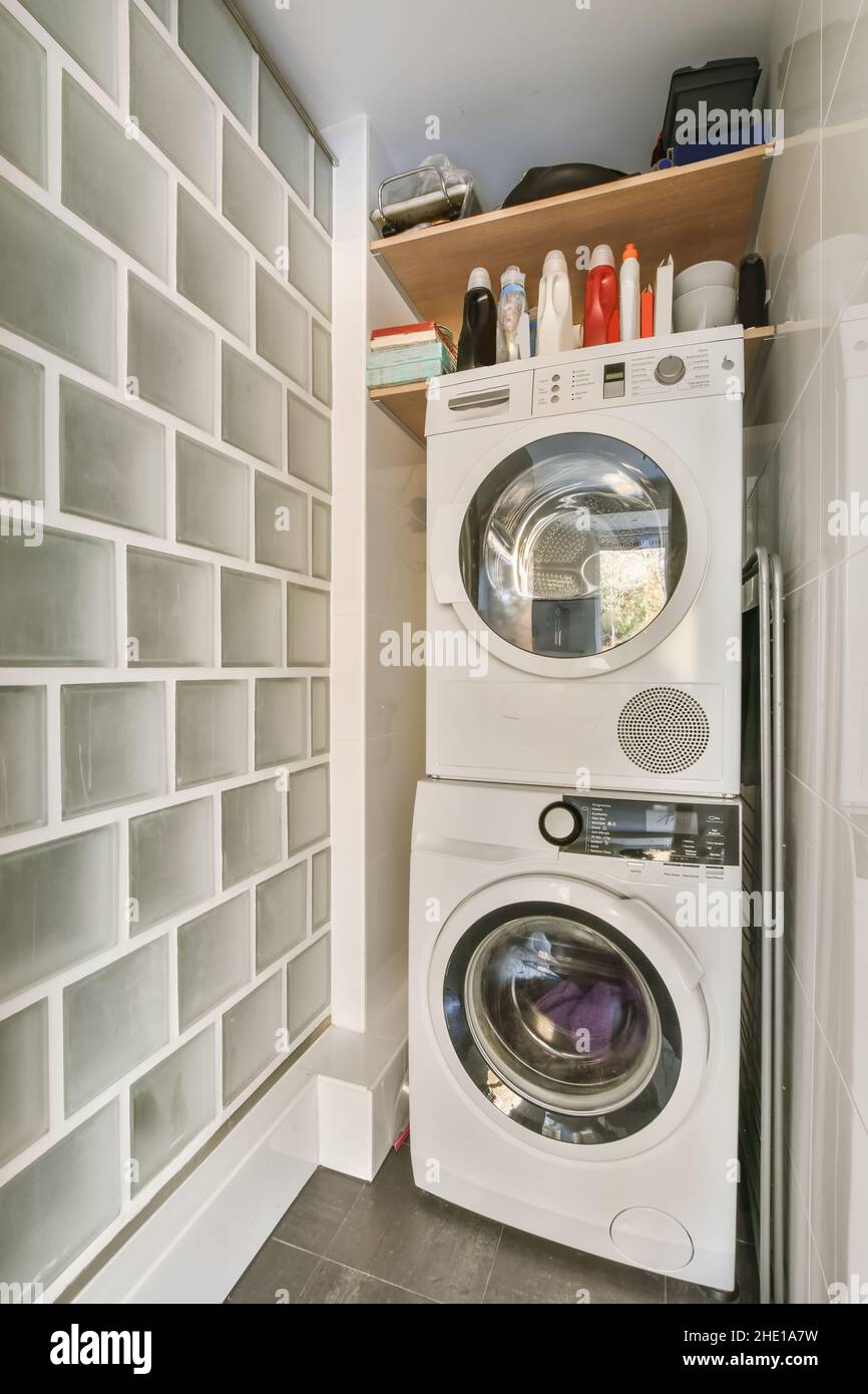 Laundry room with washing machine and tumble dryer and shelves above them  Stock Photo - Alamy