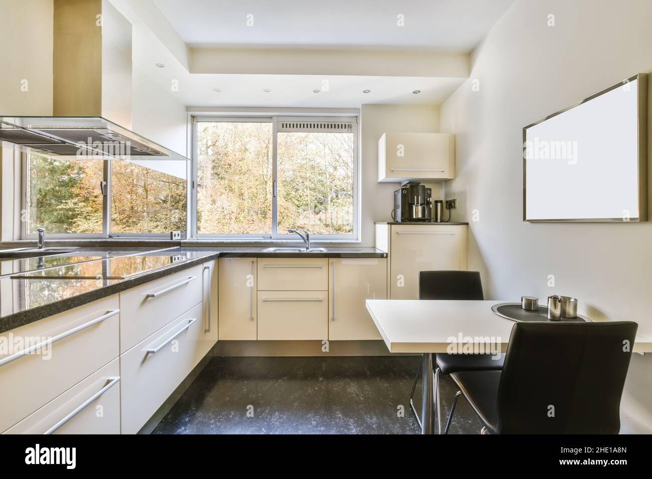 Comfortable kitchen with white kitchen unit and black countertop Stock