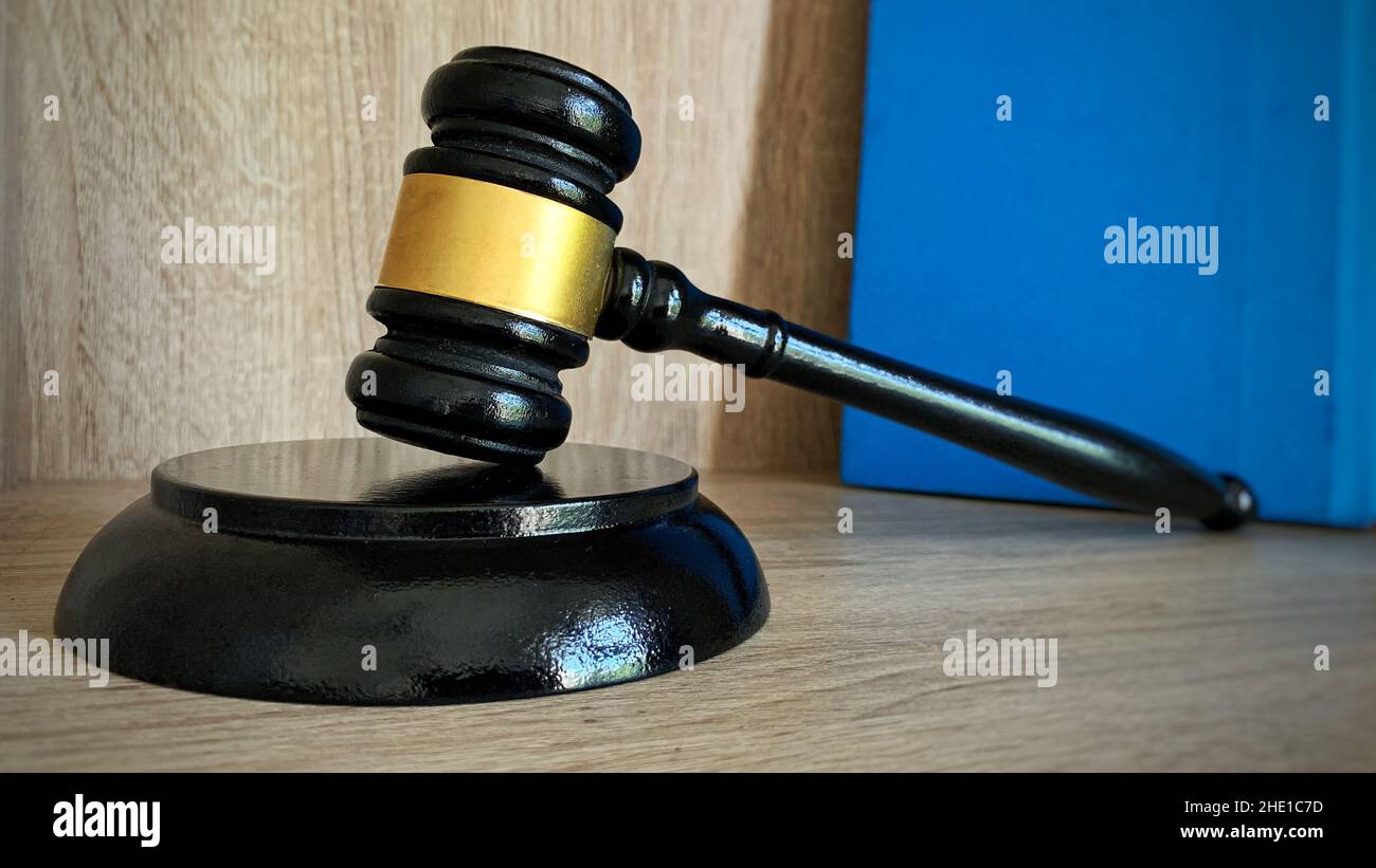 Close up of judge gavel, legality concept. With blue book and brown table background. Stock Photo