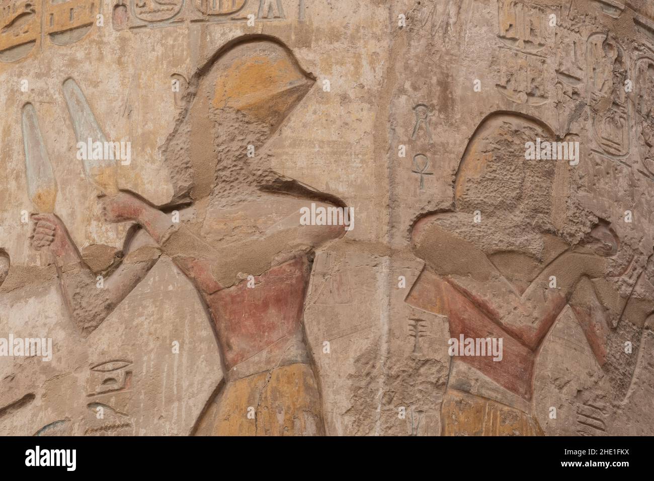 Figures in the Hypostyle hall at Karnak temple, the relief sculptures are well preserved even retaining paint although the faces were chipped off. Stock Photo