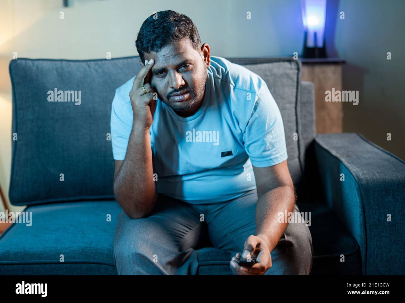 Disappointed fat man while watching sports on tv or television during late night at home - concept of lost connection while seeing live streaming web Stock Photo