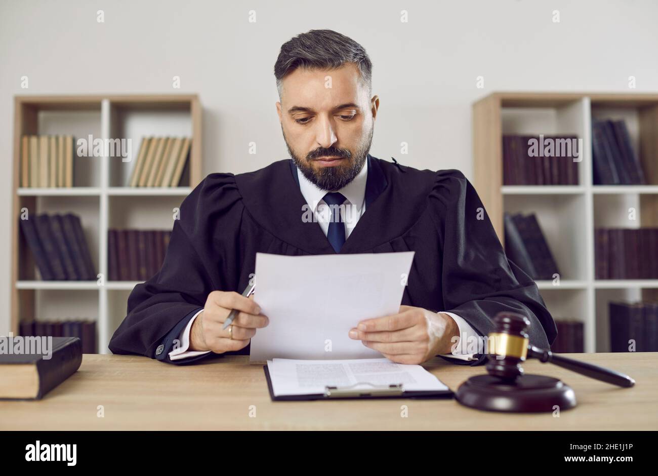 Judge, lawyer or attorney sitting at his desk and looking through some court documents Stock Photo