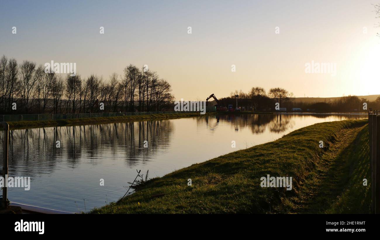 Llangennech train crash site, image of works being carried out at a distance overlooking a pool of mine water at sunset. Stock Photo
