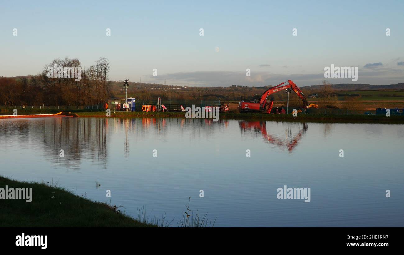 Llangennech train crash site, image of works being carried out at a distance overlooking a pool of mine water at sunset. Stock Photo