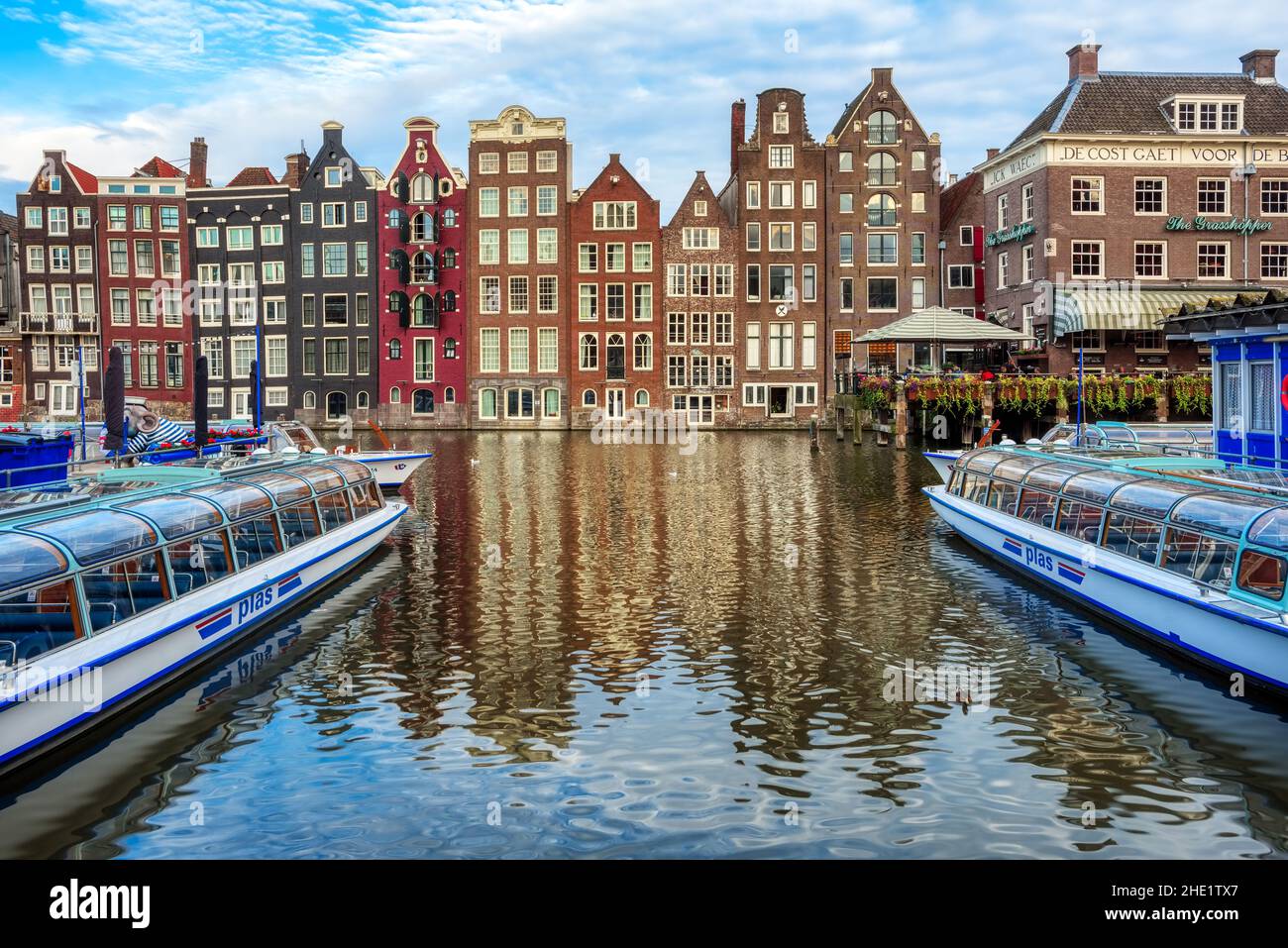 Amsterdam, Netherlands - 14 July 2020: Boats in front of the traditional brick houses on Damrak canal in the Old town of Amsterdam city. Boat trips ar Stock Photo