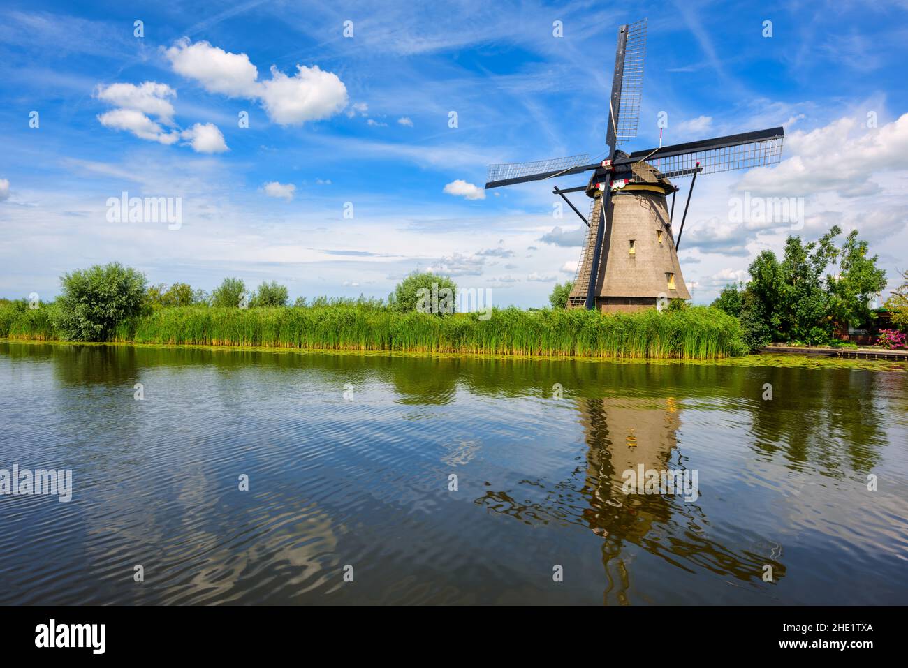 A historical wooden mill reflects in canal water in Kinderdijk windmill park, South Holland, Netherlands Stock Photo