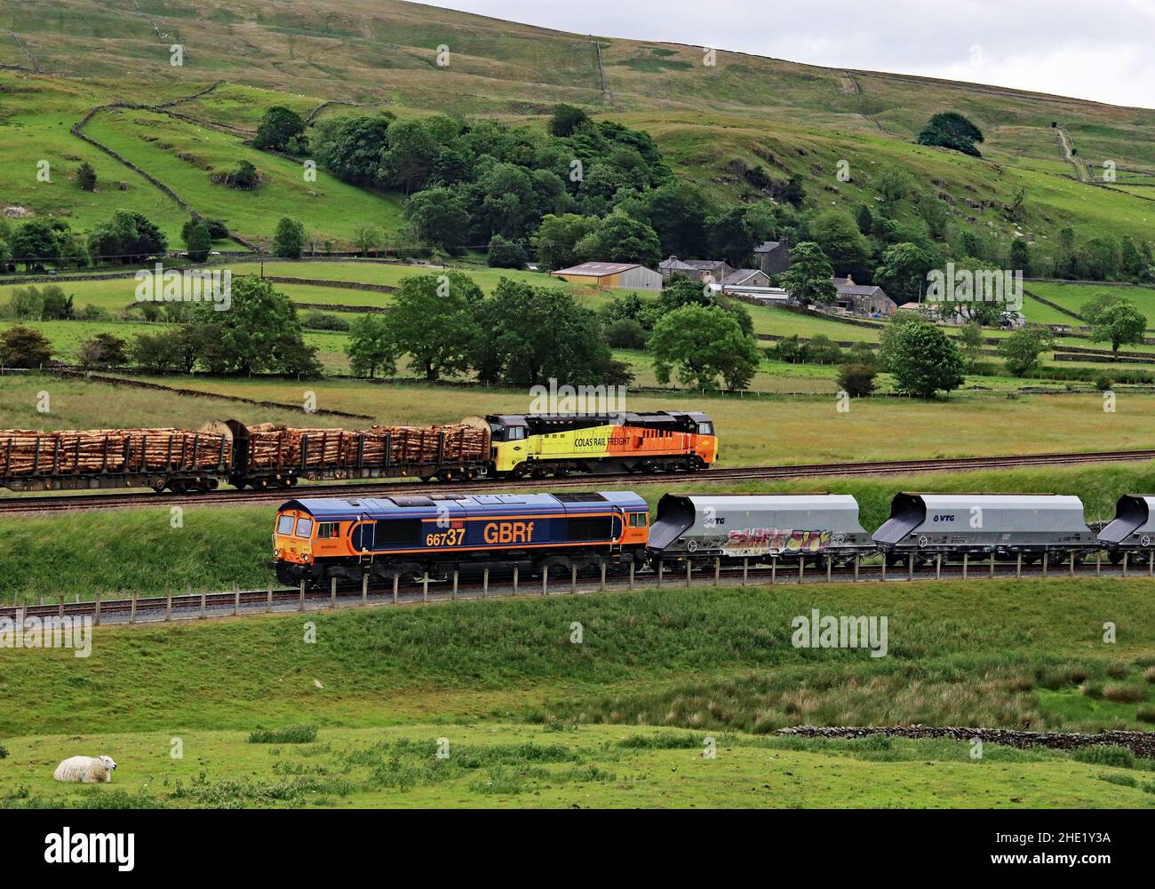 GBRF diesel locomotive no 66737 waits at Arcow quarry near Helwith Bridge in the Yorkshire Dales as Colas diesel loco 70803 passes by on the S and C Stock Photo