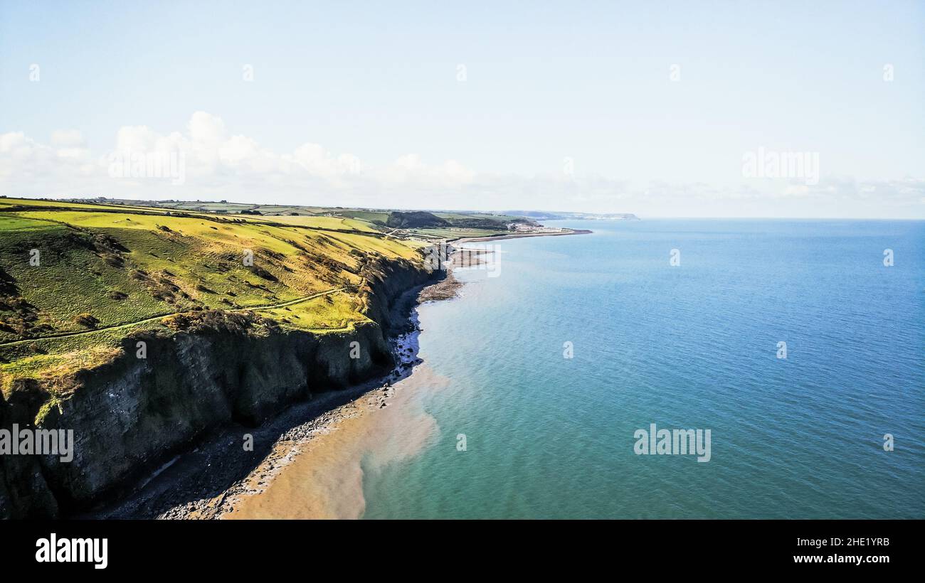 Aerial image of the Welsh coast and cliff in Llannon, Ceredigion.  Blue sky and sea, pebble beach, coastal path. Stock Photo