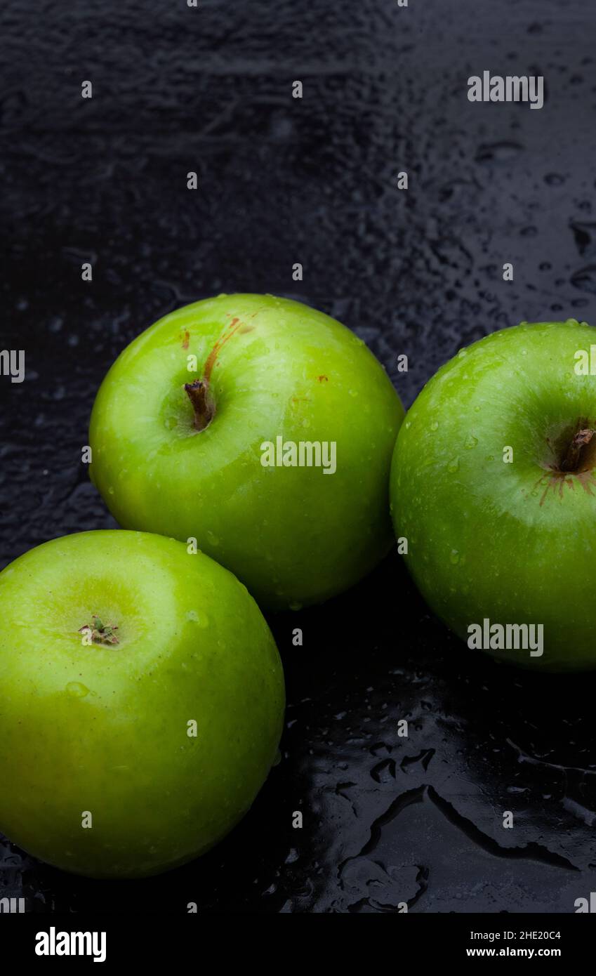 fresh and crisp green granny smith apples on black surface with water droplets Stock Photo Alamy