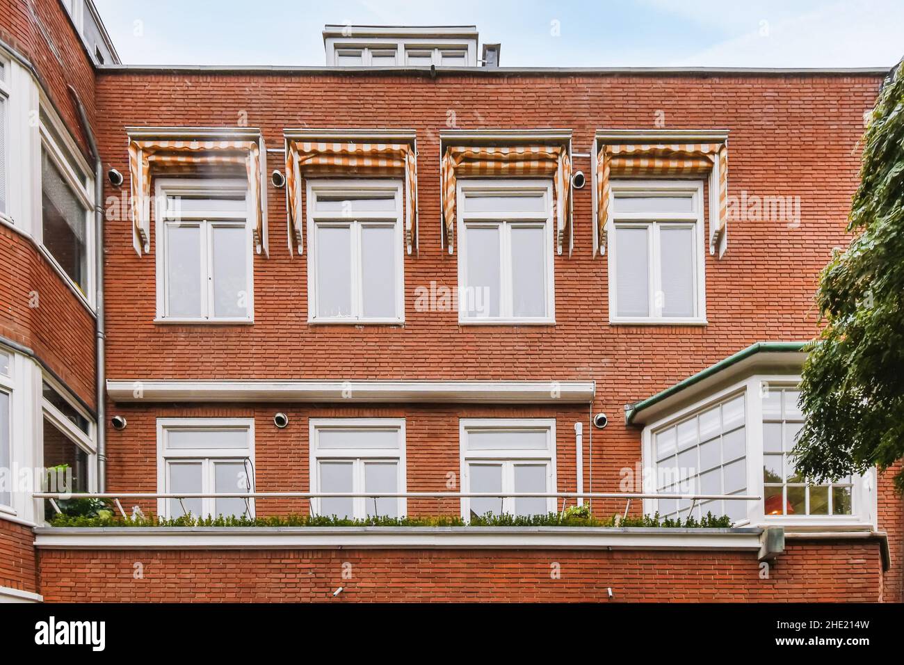 View of the roof of a multi-storey brick house with white neat windows ...