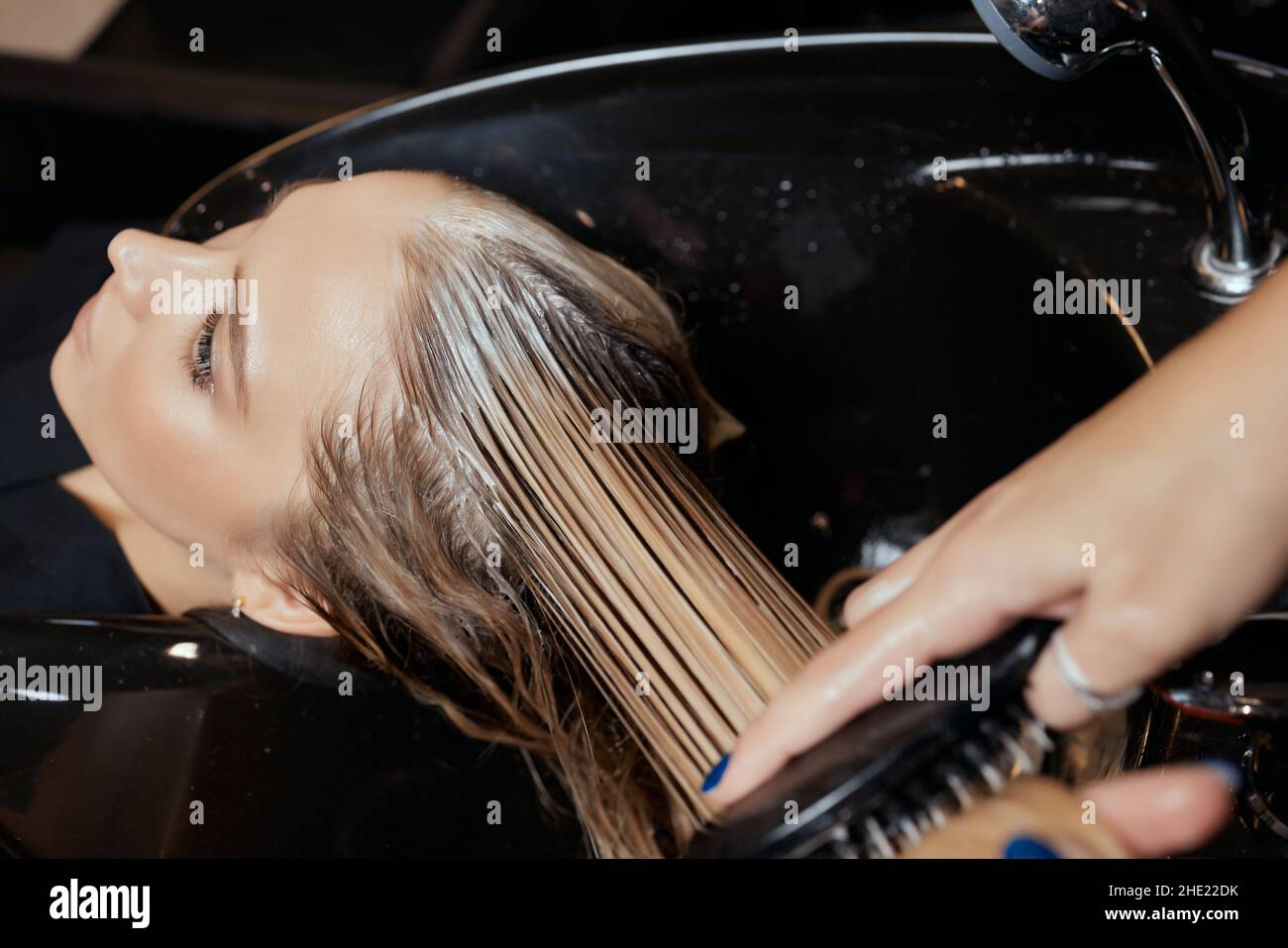 Hairdresser in beauty salon washes his client hair, before procedure of