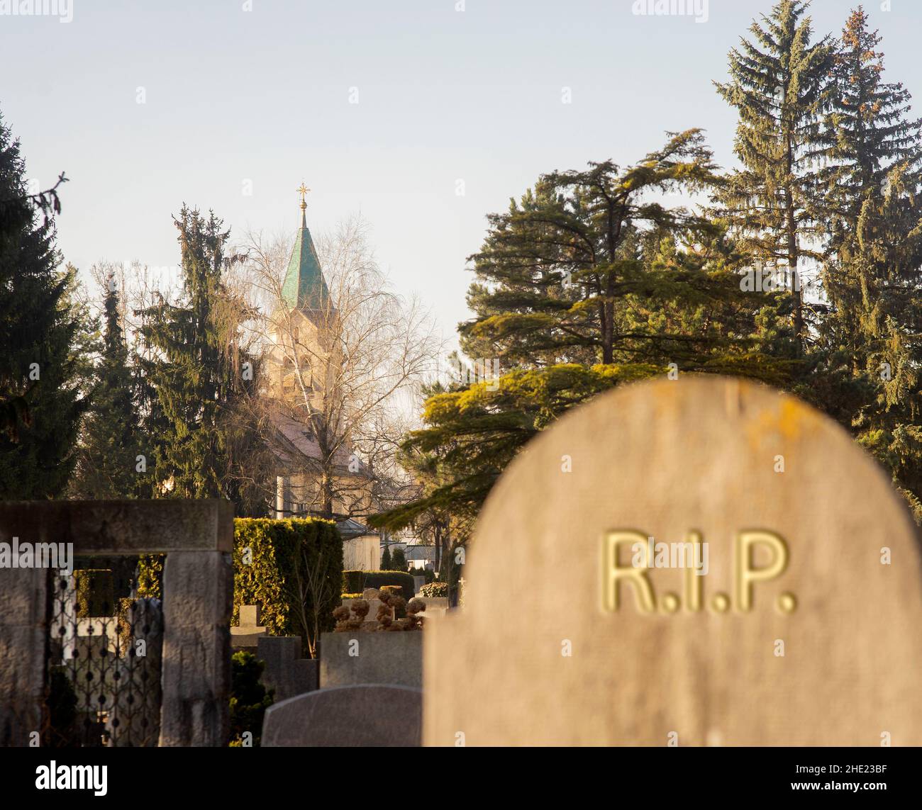 Gravestone with blurred rip sign with church in the cemetary distance. Stock Photo