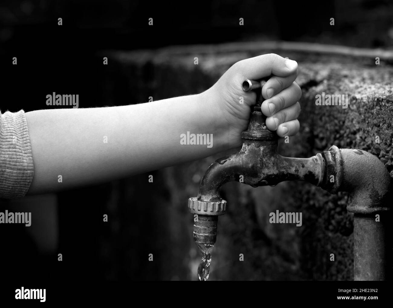 Hand from a child is turning tap water valve and letting water out