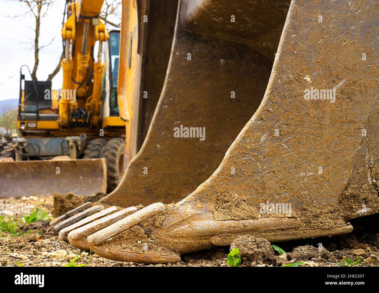 excavator machine with a bucket touching the ground in front. Stock Photo