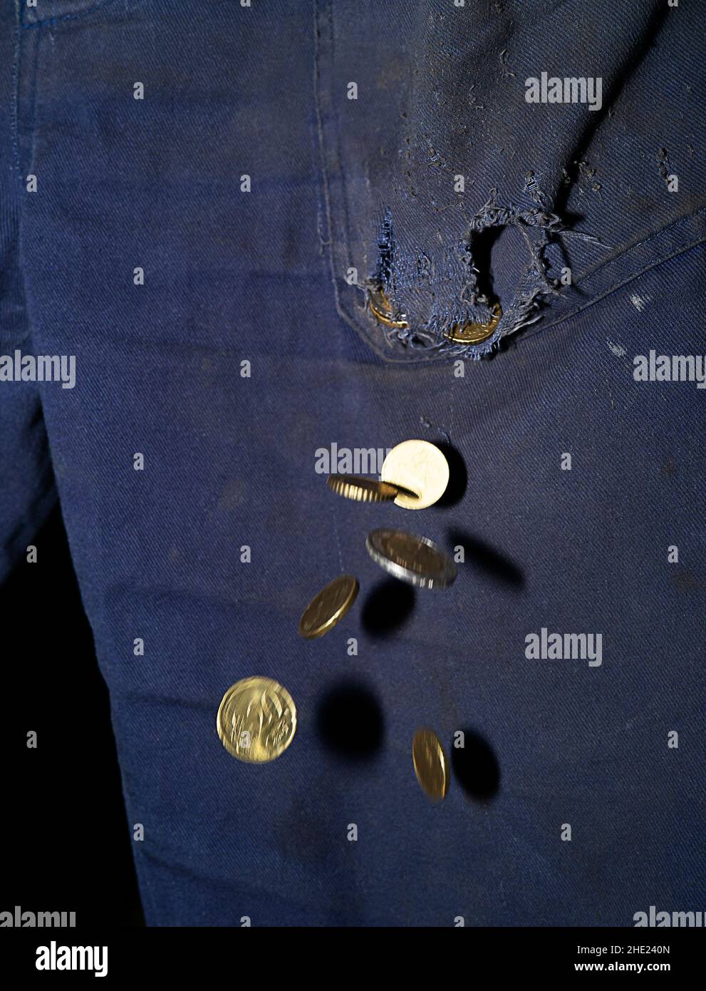 Euro coins falling from a hole in the trousers pocket. Stock Photo