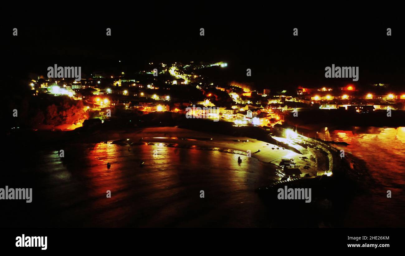 Aerial image of New Quay, Ceredigion by night.  Lights reflecting from houses and street lights over the sea and harbour Stock Photo