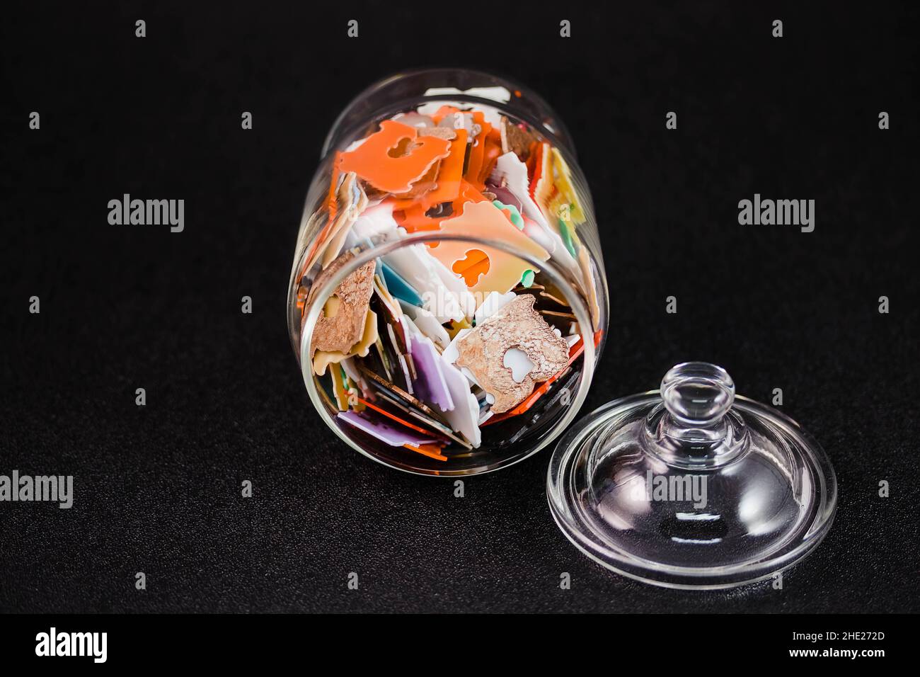 glass jar filled with lots of multicolored plastic bread tags Stock