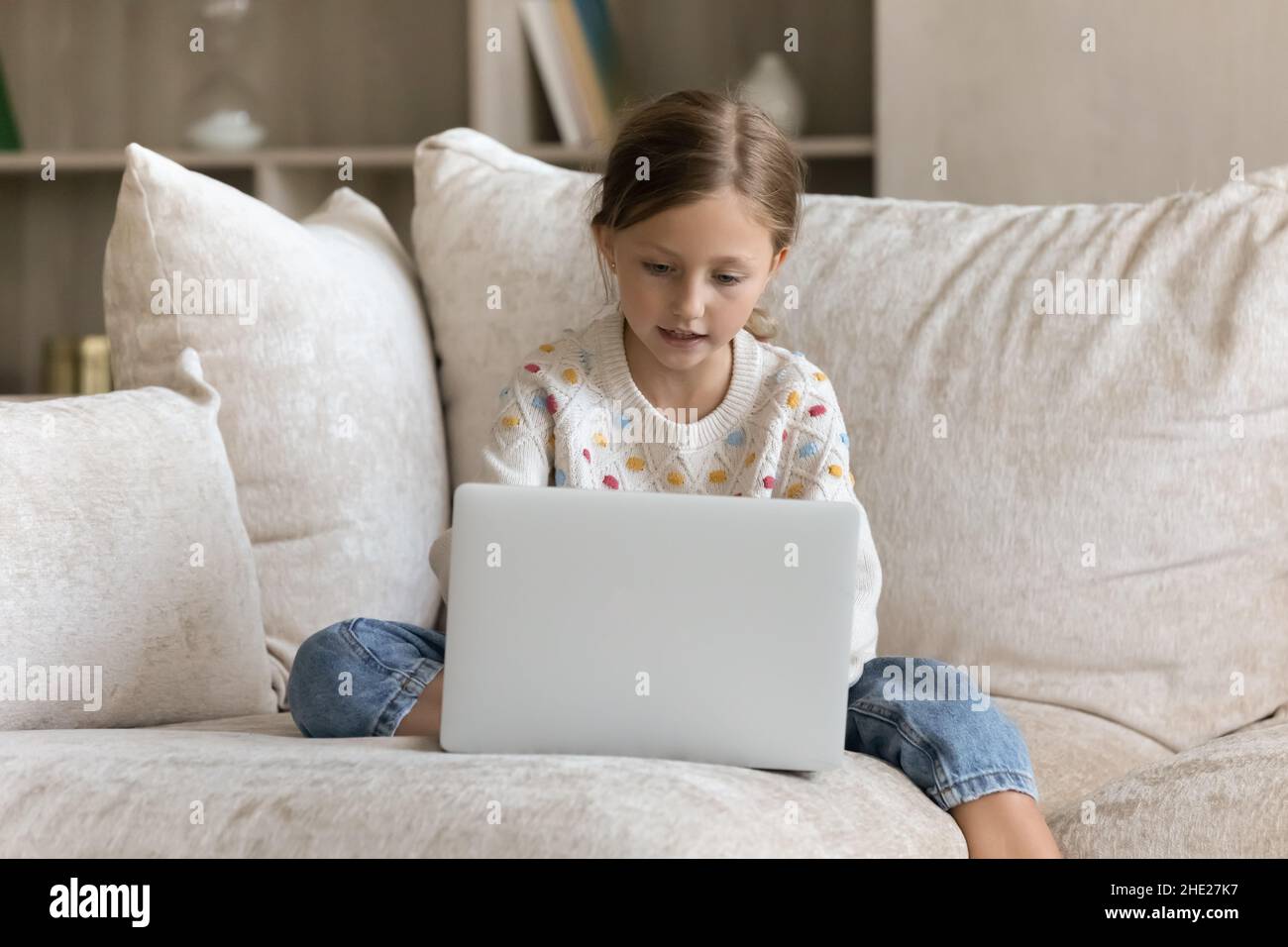 Concentrated preteen little child girl using laptop. Stock Photo