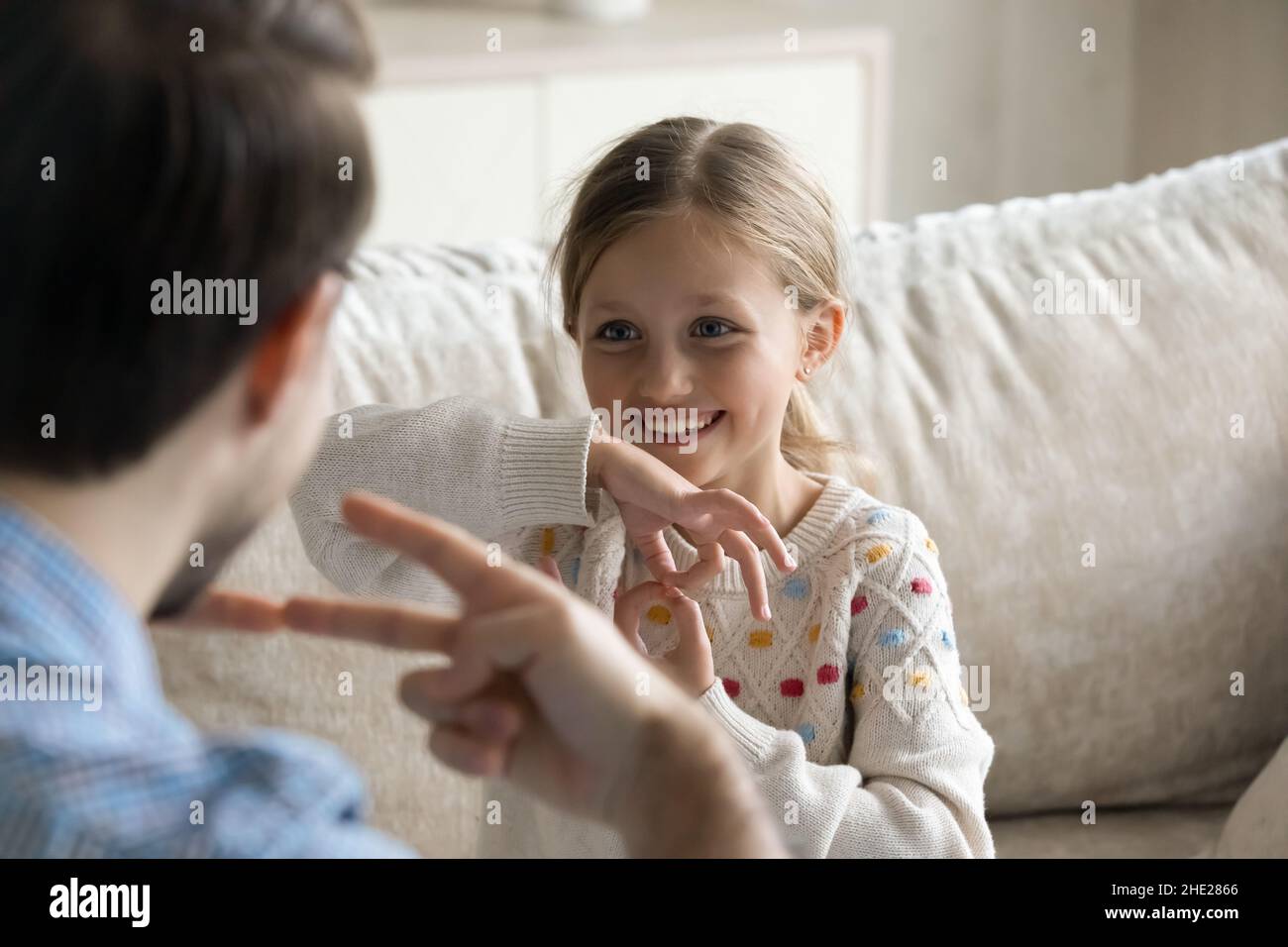 Happy small girl using sign language, communicating with father. Stock Photo