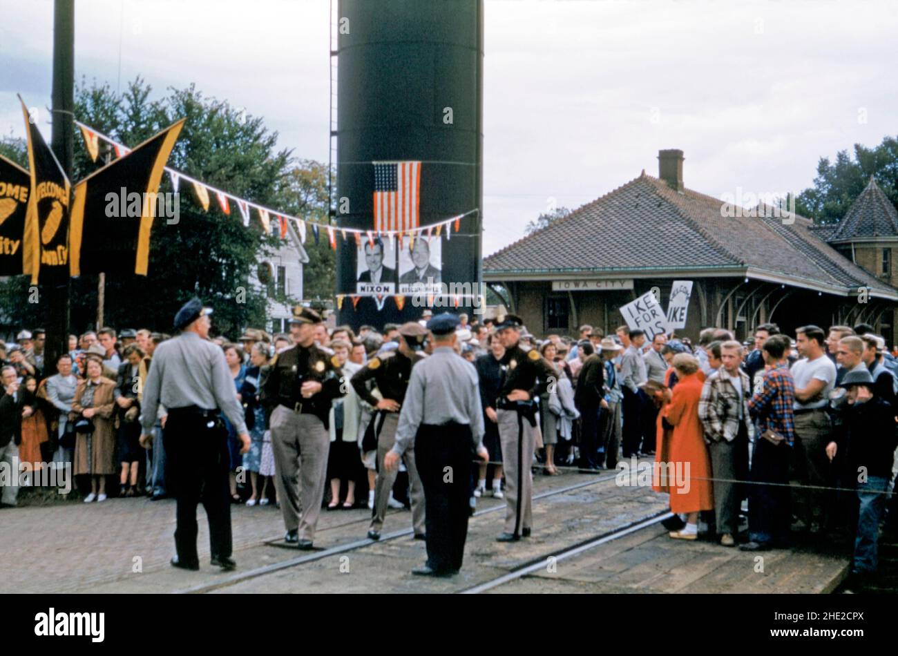 A crowd of supporters turn out on August 9th 1952 at the railroad station in Iowa City, Iowa, USA to await the arrival of Republican Dwight D Eisenhower on his campaign train in that year’s United States presidential election. Placards have slogans on them saying ‘Ike for us’ and ‘Welcome Ike’. Posters of Eisenhower and Richard Nixon, Eisenhower’s running mate, are on show.  Eisenhower won a landslide victory over Democrat Adlai Stevenson. This image is from an old American amateur Kodak colour transparency – a vintage 1950s photograph. Stock Photo