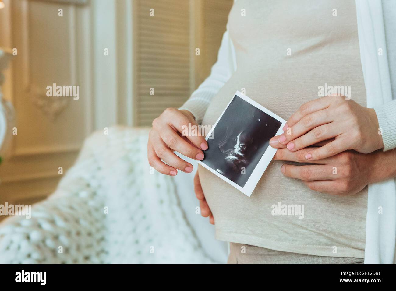 Family planning. Cropped shot of loving husband hugging his pregnant wife holding ultrasound scan in hands, man and woman in anticipation of waiting f Stock Photo