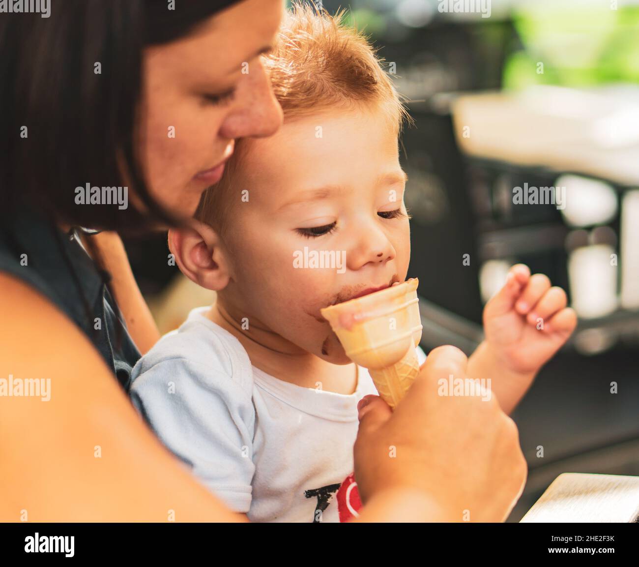 Closeup shot of a young boy and woman eating ice cream at a bar Stock Photo