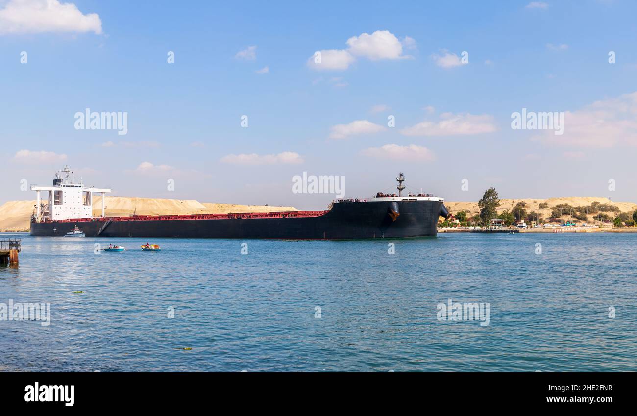 Bulk carrier ship with black hull passes the Suez Canal, Ismailia, Egypt Stock Photo