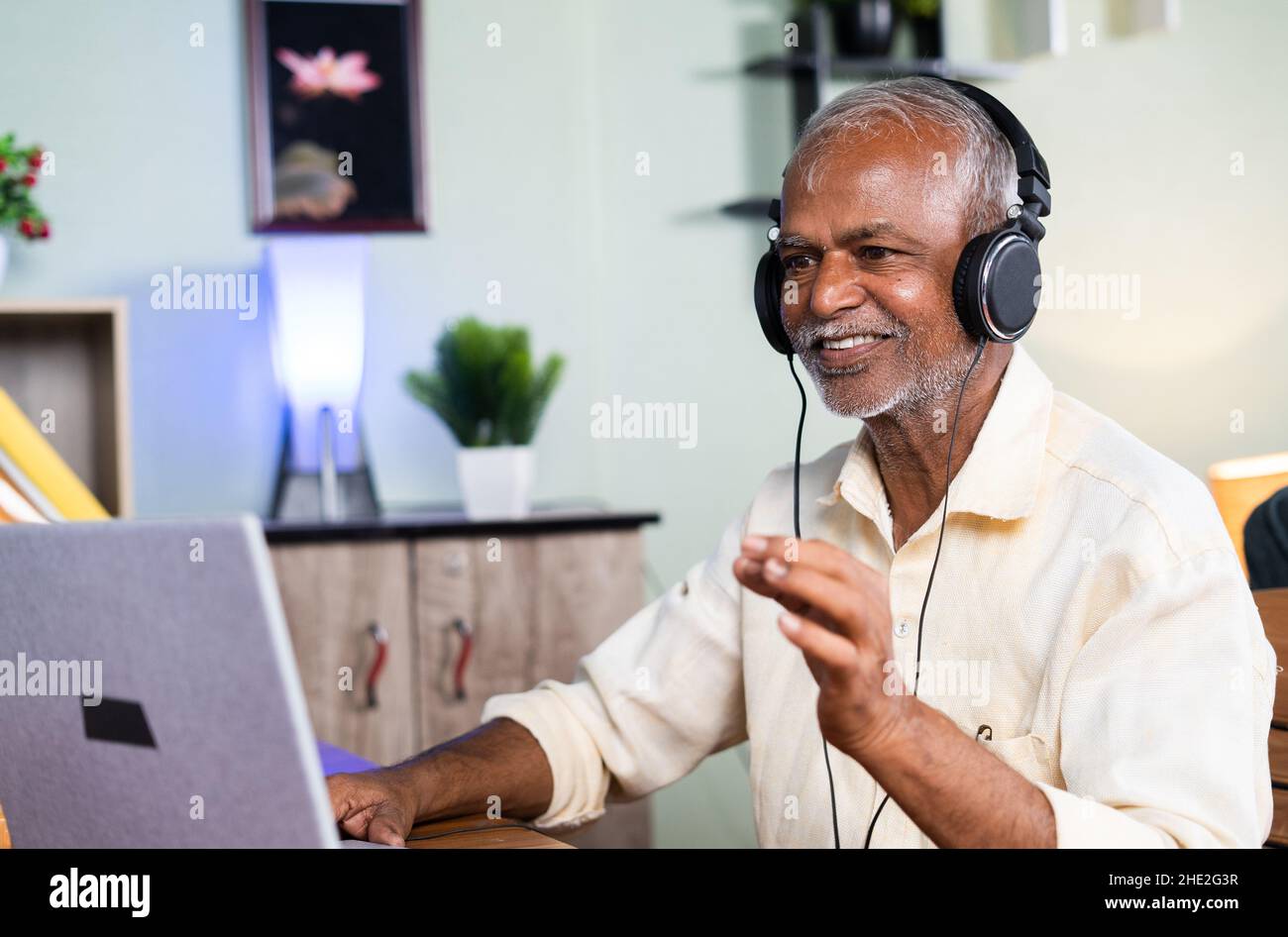 old man enjoying watching music videos on laptop at home - Concept of active senior people, cheerful and healthy retired lifestyle. Stock Photo